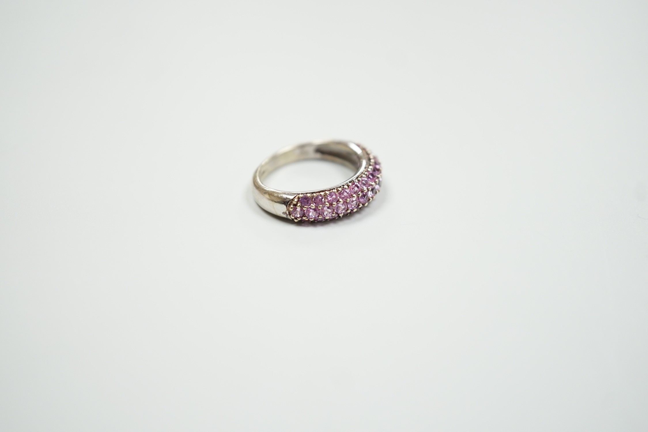 A modern 18ct white gold and pink stone cluster set half hoop ring, size J, gross weight 4.2 grams.